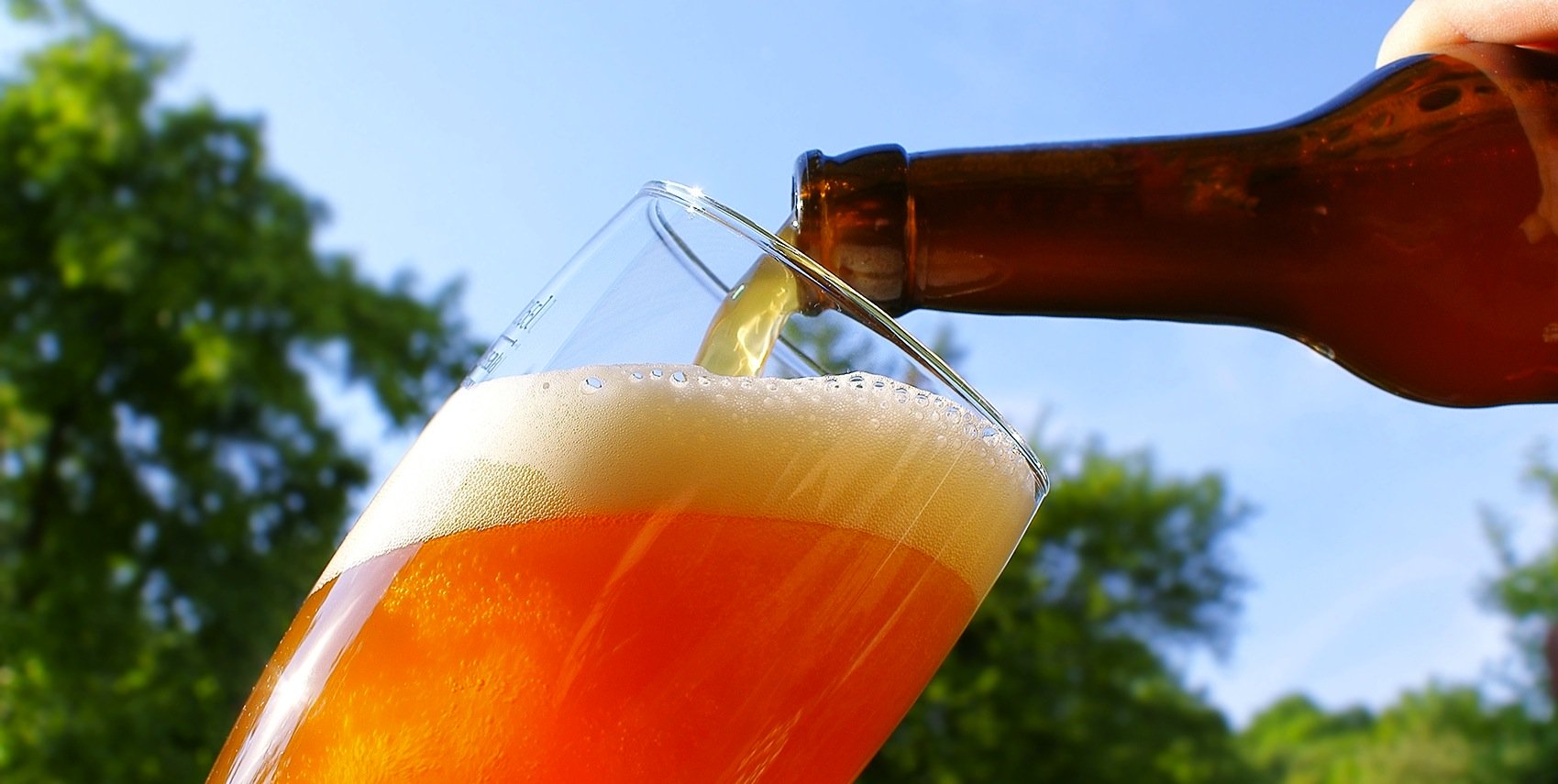 Bier, das aus einer Flasche in ein Glas gegossen wird 