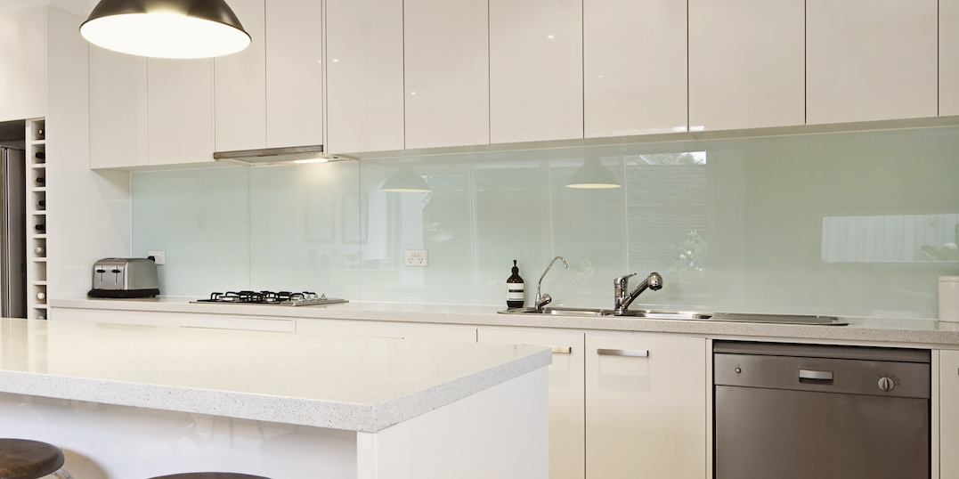 Weiße Küche mit pastellfarbener Glasküchenrückwand 