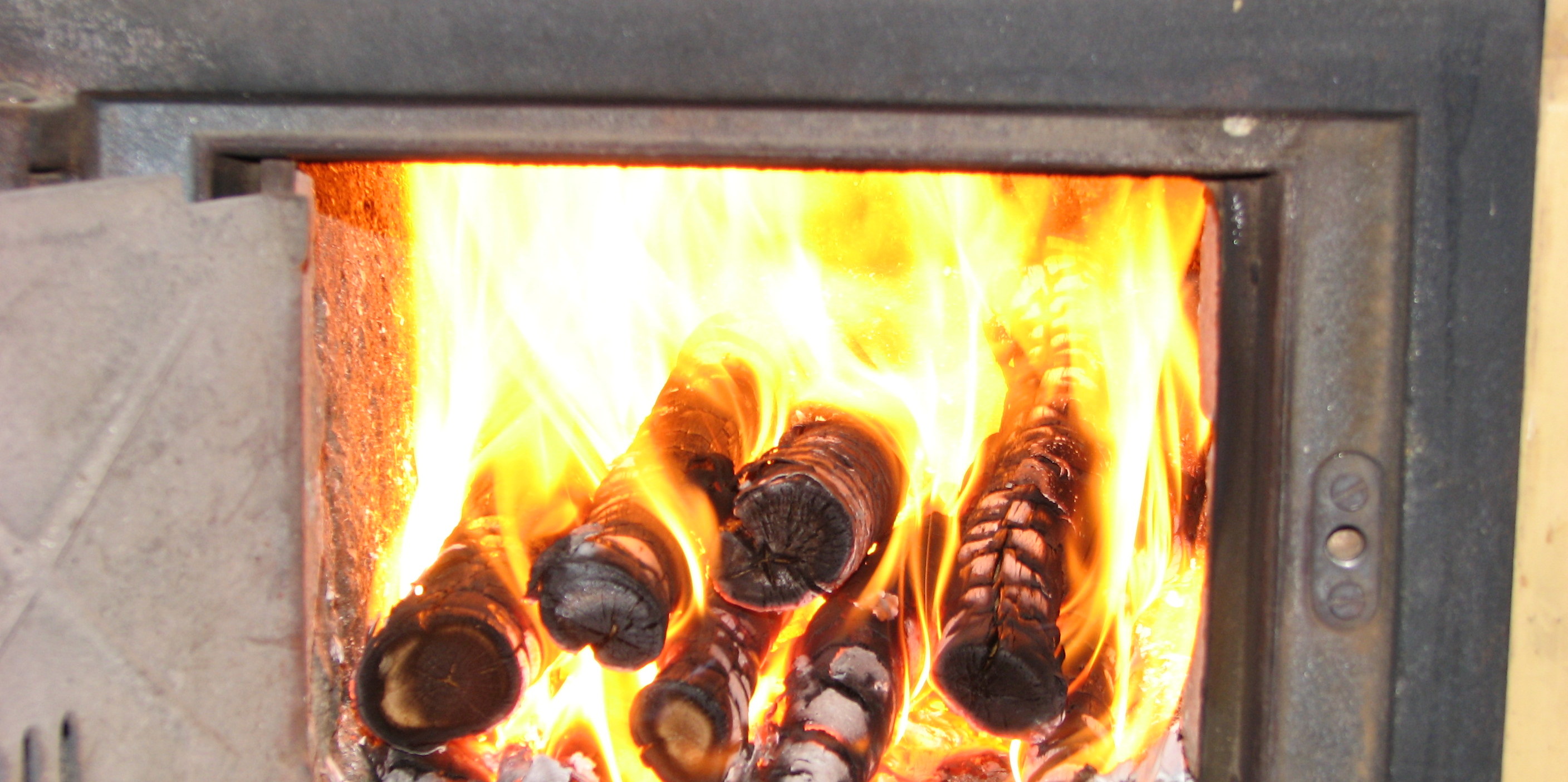 Ofene Kachelofenklappe mit brennenden Holzstücken