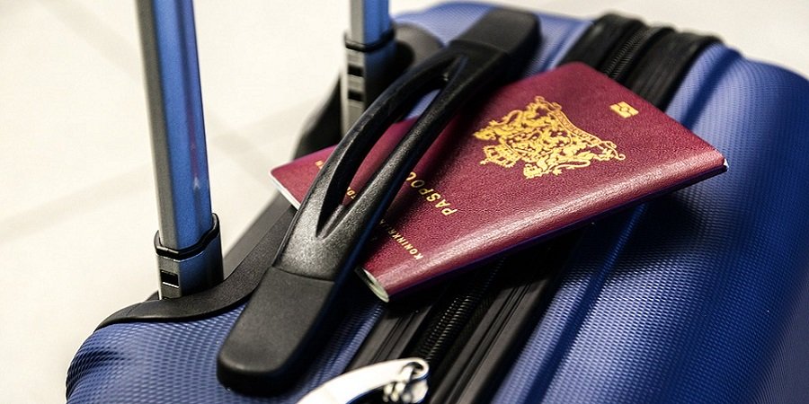ein blauer Reisekoffer, darüber befindet sich ein Reisepass eingeklemmt