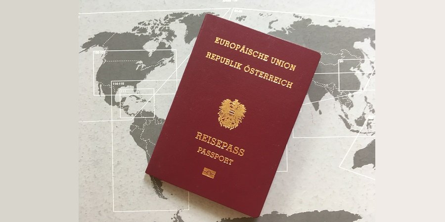 Reisepass aus der Republik Österreich ist zu sehen, dahinter eine weltkarte