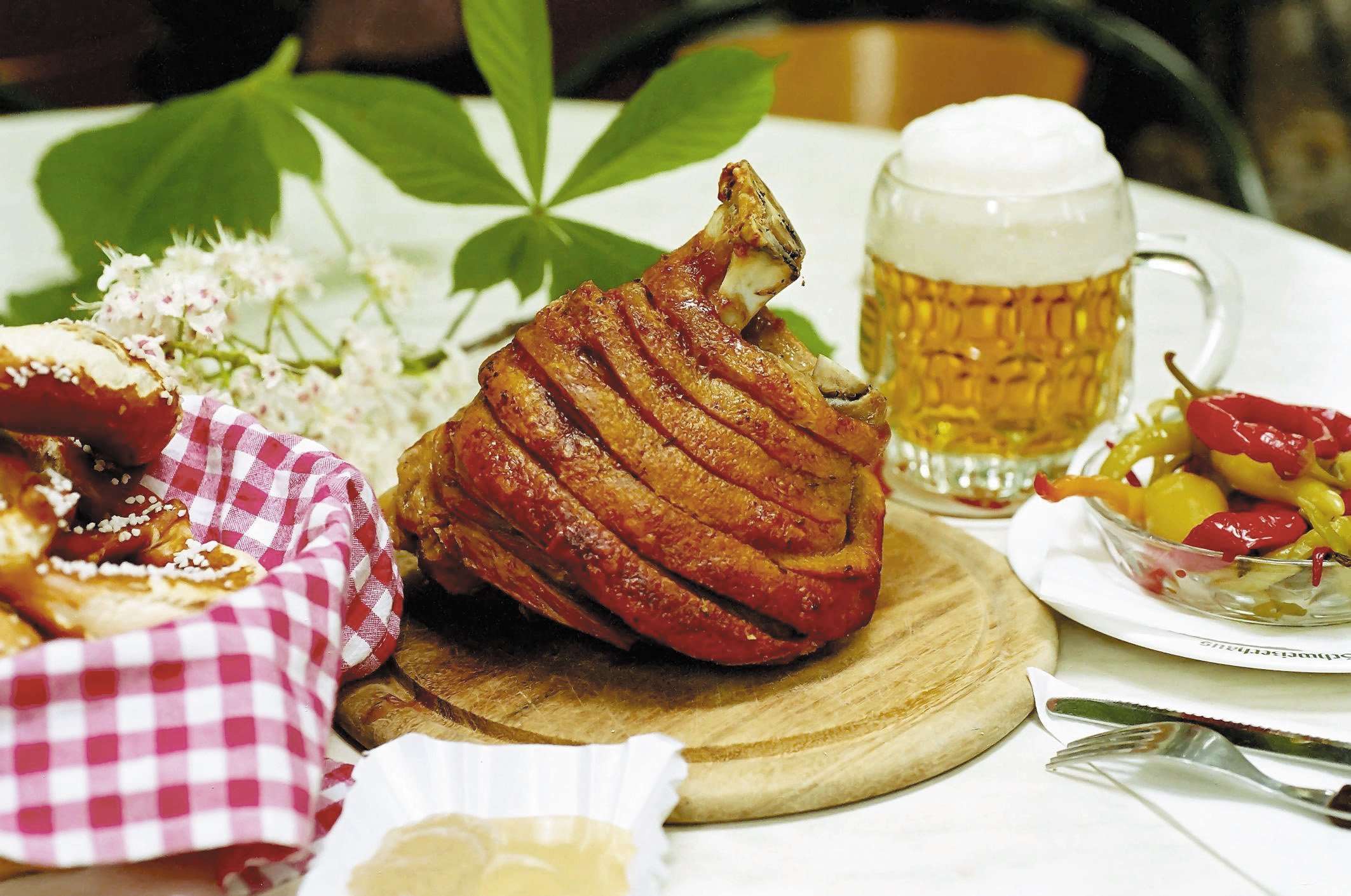 Stelze, Beilagen und Bier auf einem Tisch im Schweizerhaus im Wiener Prater