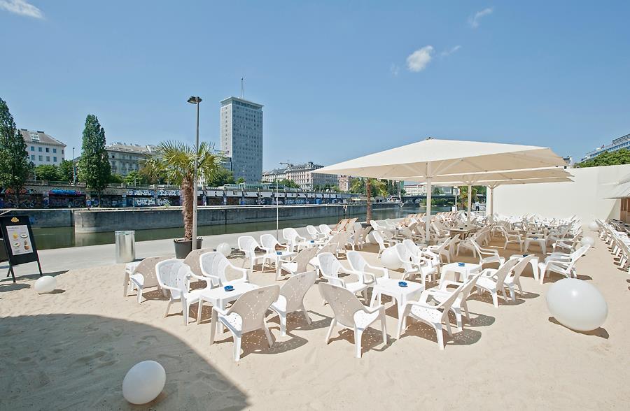 Strandterasse mit vielen Stühlen und Sonnenschirmen an einem schönen Tag am Donaukanal