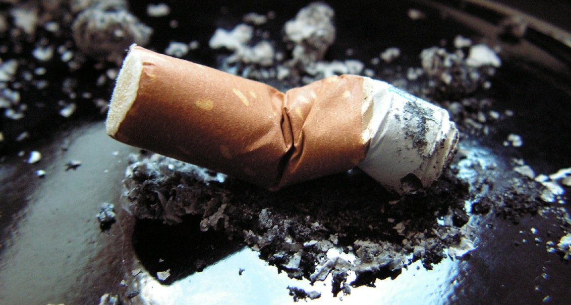 Ausgedämpfte Zigarette in einem schwarzen Aschenbecher