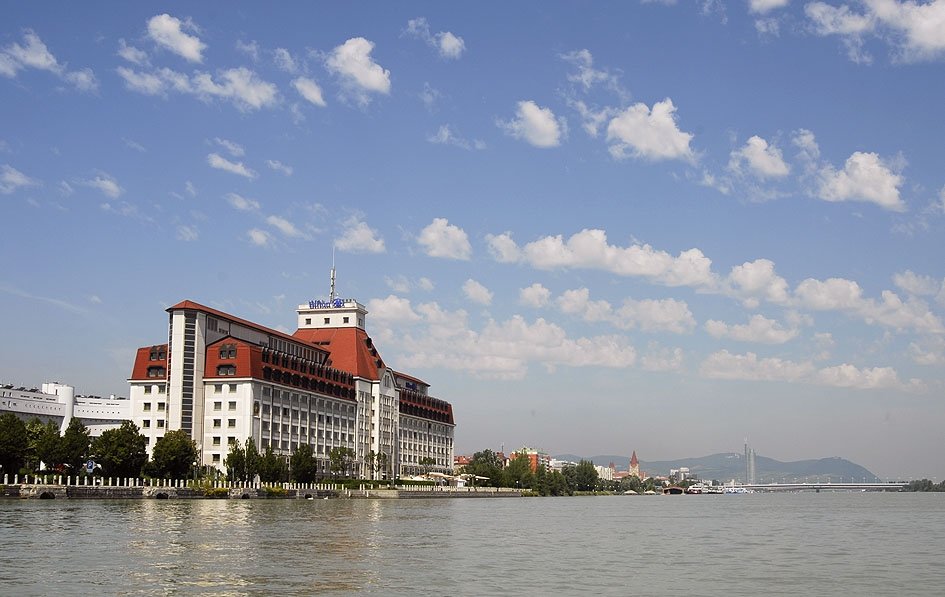 Auf dem Bild ist das direkt am Ufer der Donau gelegene Hilton Vienna Danube Hotel zu sehen. 