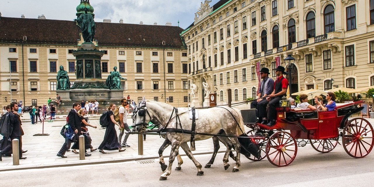 Fiaker mit Gästen fährt durch Wiener Hofburg