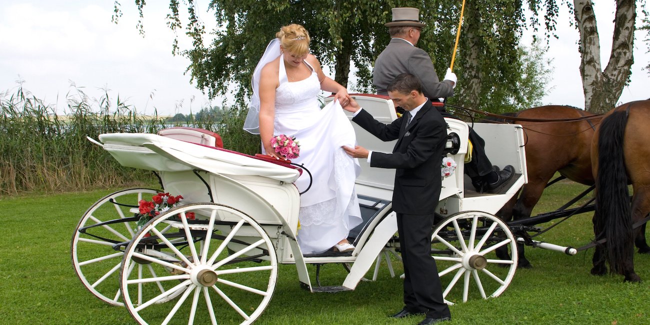 Braut steigt aus Hochzeitskutsche aus