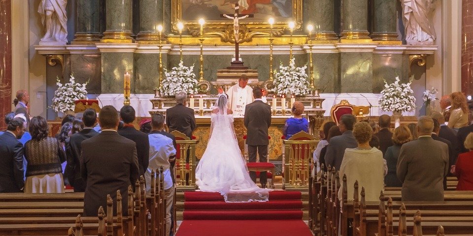 Brautpaar vor dem Traualtar auf den Kirchenbänken sitzen die Hochzeitsgäste