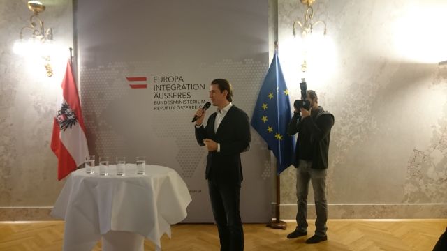 Sebastian Kurz neben Tisch und zwischen Österreich-Flagge und EU-Flagge