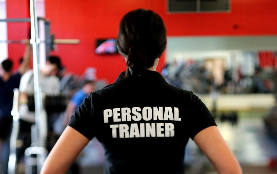 Personal Trainer im Fitnessstudio mit schwarzem Shirt auf dem Personal Trainer steht