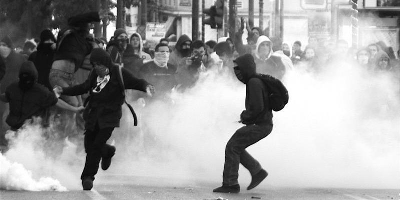 Vermummte griechische Demonstranten im Tränengas. 