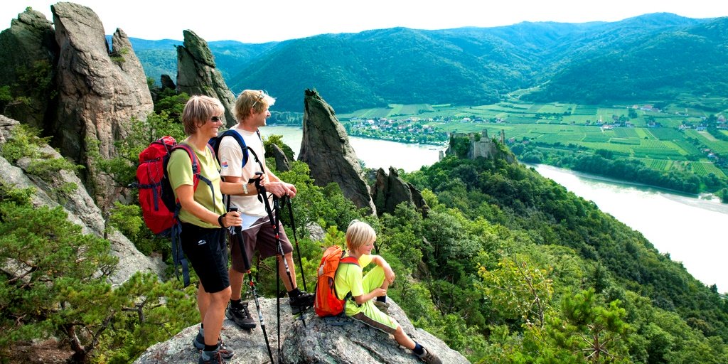 Familie sitzt auf Stein mit Blick auf's Tal und die Donau