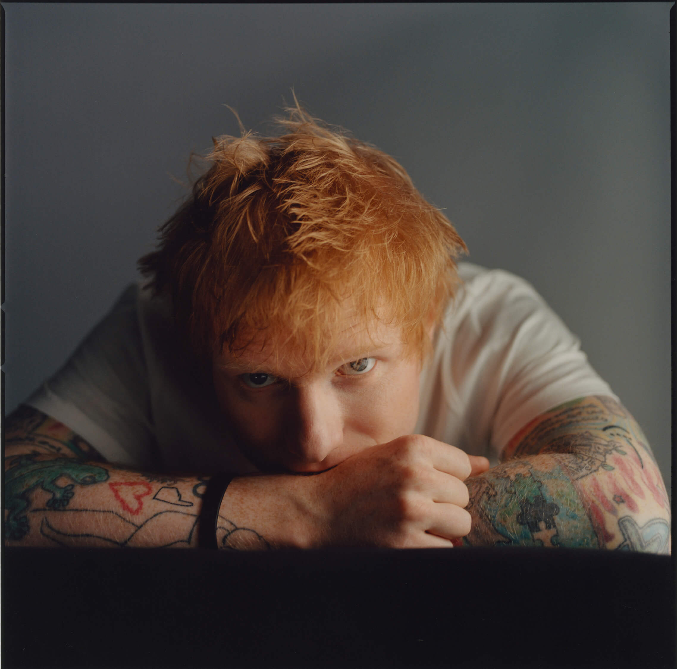 Musiker Ed Sheeran legt den Kopf auf die Unterarme