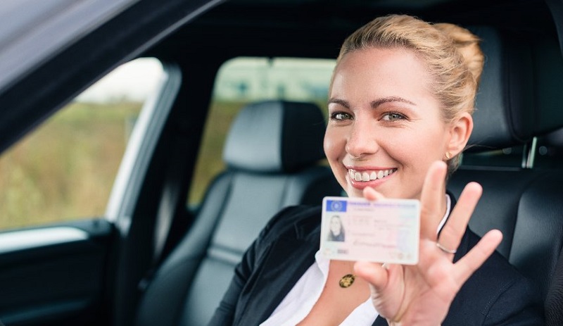 Frau hält lachend Scheckkarten-Führerschein in die Kamera