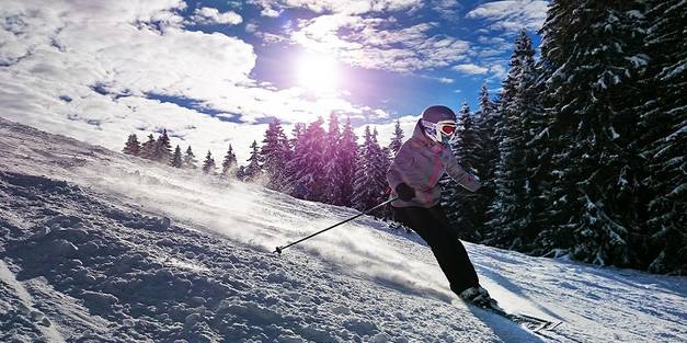 Mädchen fährt verschneiten Hand mit Skiern hinunter