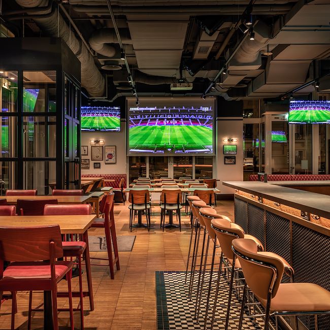 Eine leere Bar mit vielen TV-Bildschirmen auf denen Fußball übertragen wird.