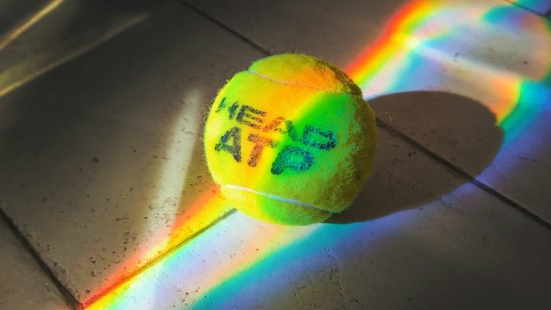 Tennisball, der von einem Regenbogen beleuchtet wird