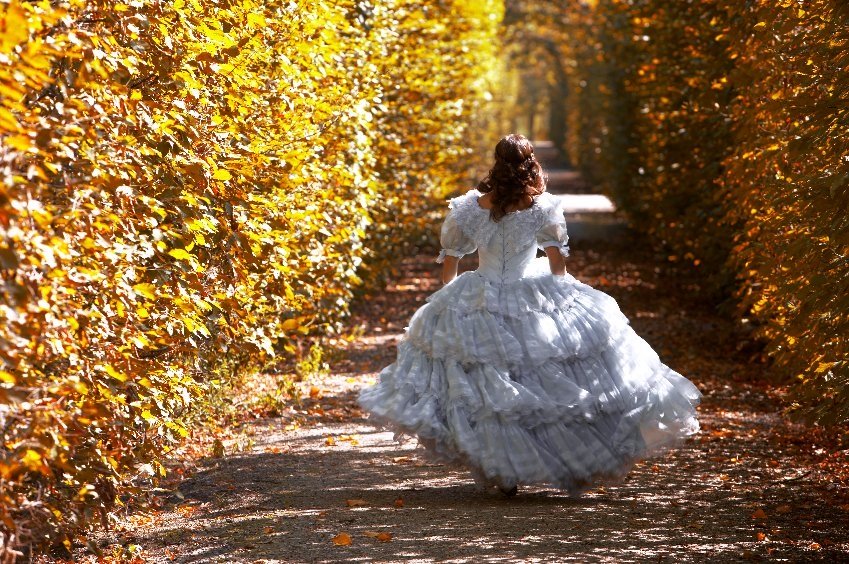 Frau im Sisi-Kleid läuft durch das herbstliche Schönbrunn