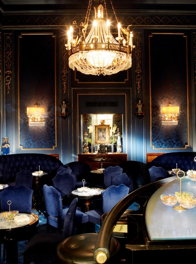 Ein Bar mit blauem Interieur, einem großen Luster und Spiegel.