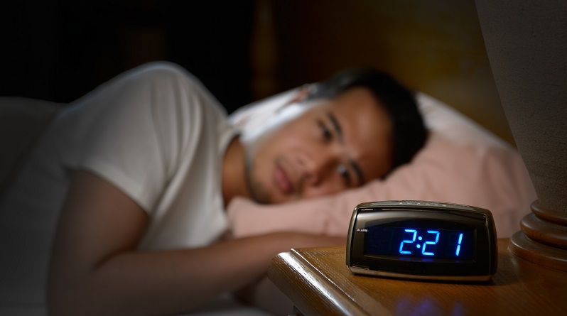 Mann kann nachts nicht schlafen, auf der Uhr zeigt es bereits halb 3 Uhr morgens
