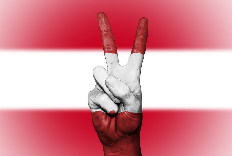 Österreichische Flagge mit Peace-Zeichen zeigenden Fingern