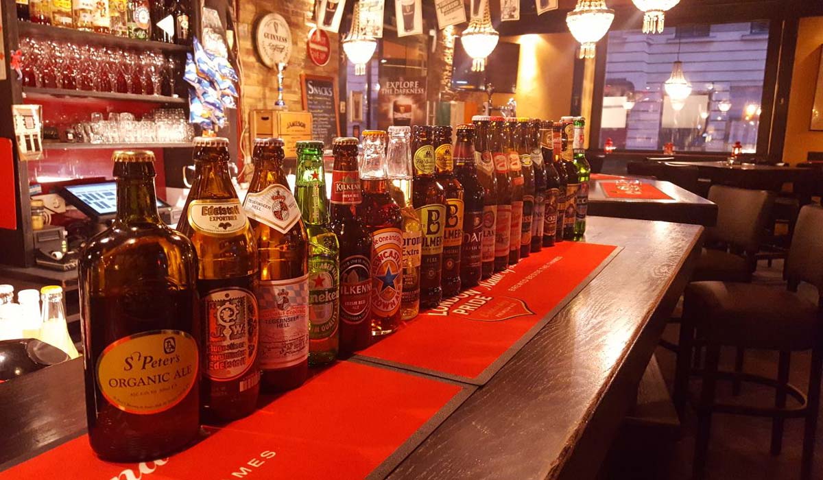 Unterschiedliche Bierflaschen stehen auf einer Bar in einem Lokal.