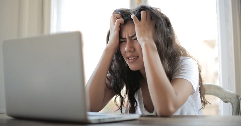 Das Bild zeigt eine Frau vor einem Computer, die sich die Haare rauft.